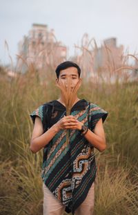 Portrait of man holding crops standing at farm