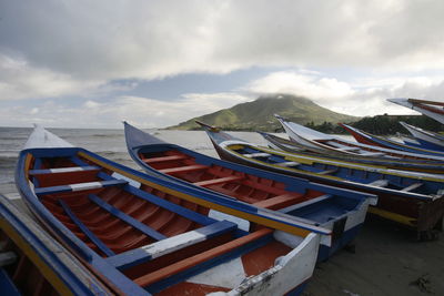 Boats in river against cloudy sky