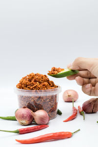 Close-up of hand holding food over white background