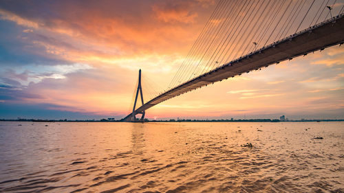 Scenic view of bridge over sea against sky during sunset