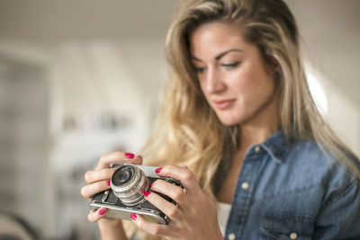 Young woman holding camera at home