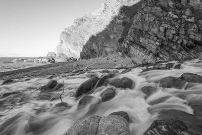 Black and white photo of the river heddon flowing onto the beach at heddons mouth in exmoor