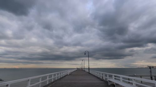View of bridge over calm sea against cloudy sky