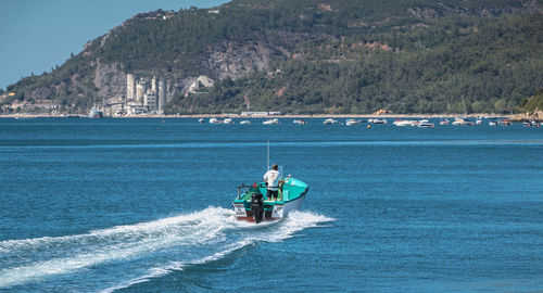 Man riding motorcycle on sea against mountain