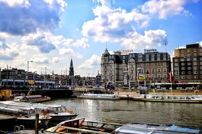 Boats moored at harbor by buildings against sky