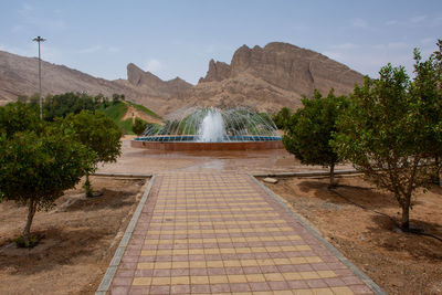 Footpath amidst trees and mountains against sky