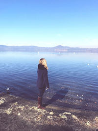 Rear view of woman standing by sea against sky