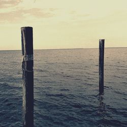 Close-up of wooden post in sea against sky