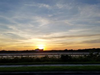 View of landscape against cloudy sky during sunset