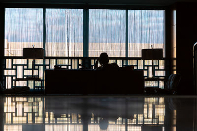 Rearview of silhouette woman sitting at the window in the lobby