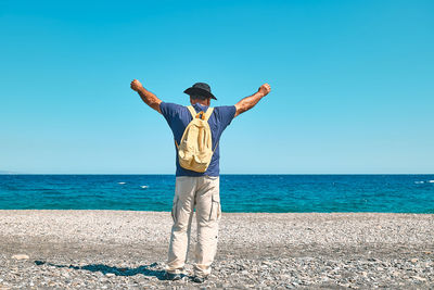 Happy tourist man enjoying freedom with open hands on sea. wellness, success, freedom and travel