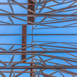 Low angle view of electricity pylon against blue sky