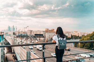 Rear view of woman standing by railing against sky