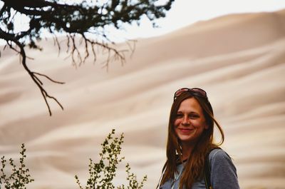 Portrait of smiling woman against sand dune