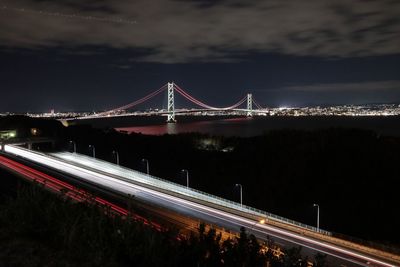 Illuminated suspension bridge in city against sky at night