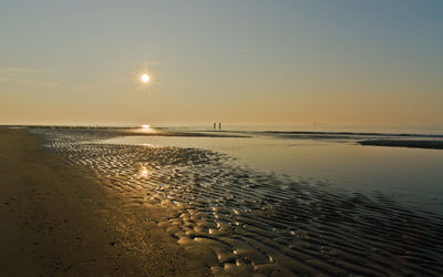 Empty north sea beach in the light of the setting sun. breakwater and ship on the horizon.