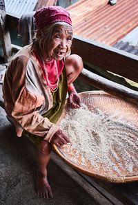 High angle view of woman cleaning grain while sitting on bench