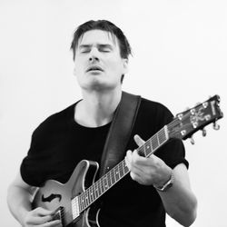 Young man playing guitar against white background