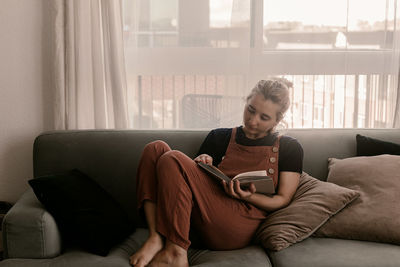 Young man using mobile phone while sitting on sofa at home