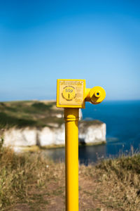 Information sign on field by sea against clear sky