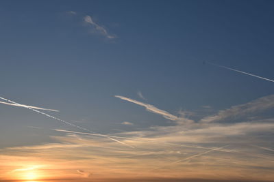 Low angle view of vapor trail in sky during sunset