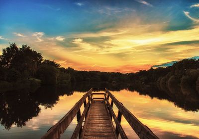 Pier over lake against sky during sunset