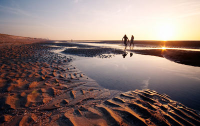 Silhouette couple walking on beach