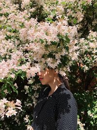 Low angle view of woman standing by flowering tree