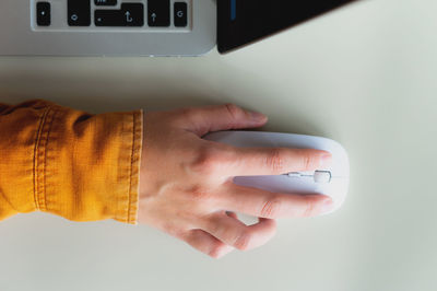 From above, close-up photo of a hand with a wireless white computer mouse to search for the