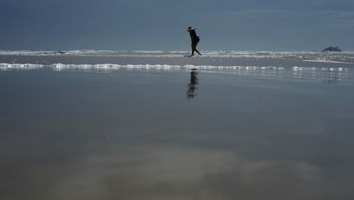 Silhouette man standing on beach against sky