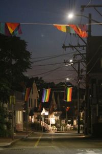 Illuminated street by houses against clear sky