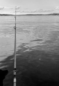 Fishing rod on pole by sea against sky