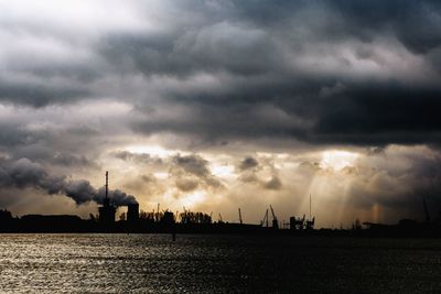 Silhouette of cranes against dramatic sky