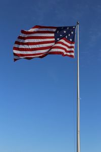 Low angle view of flag against blue sky