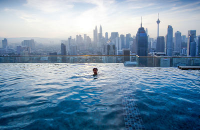 Man in swimming pool against buildings in city