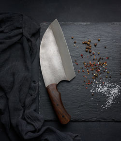 Large kitchen knife on a black graphite board and spices, top view