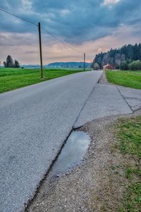 Road by grass against sky