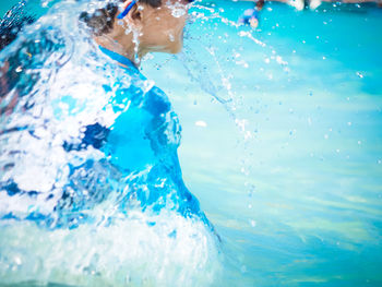 Midsection of boy swimming in pool