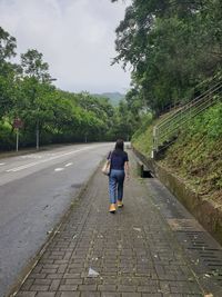 Rear view of woman walking on footpath against sky