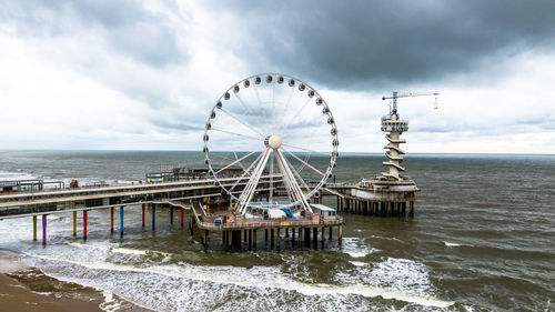 Ferris wheel by sea against sky