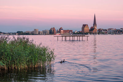 View of buildings at waterfront during sunset