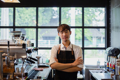 Portrait of young man standing in cafe against window