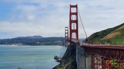 Golden gate bridge over river against cloudy sky