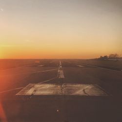 Airplane on road against sky during sunset