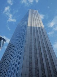 Low angle view of skyscrapers against cloudy sky