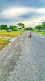 Road passing through landscape against cloudy sky