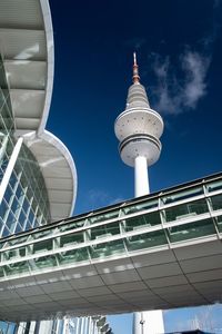 Low angle view of modern building and tv tower against sky.