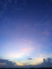 Low angle view of vapor trail in sky during sunset