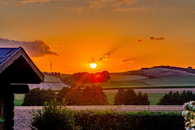 Houses on field against orange sky