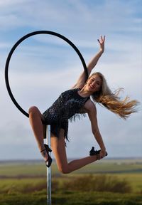 Full length of woman with arms raised against sky